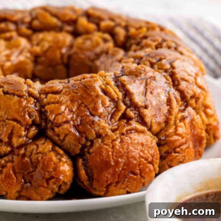Gooey Gluten-Free Monkey Bread Bliss 6 Side on view of monkey bread on a white plate with a white bowl of caramel off to one side.
