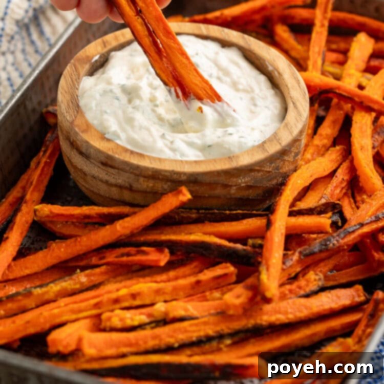 Carrot fry from a tray of them being dipped into a wooden bowl of creamy dip.