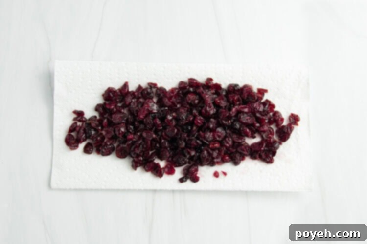 Overhead view of rehydrated cranberries resting on paper towels to drain excess water, ready for baking.