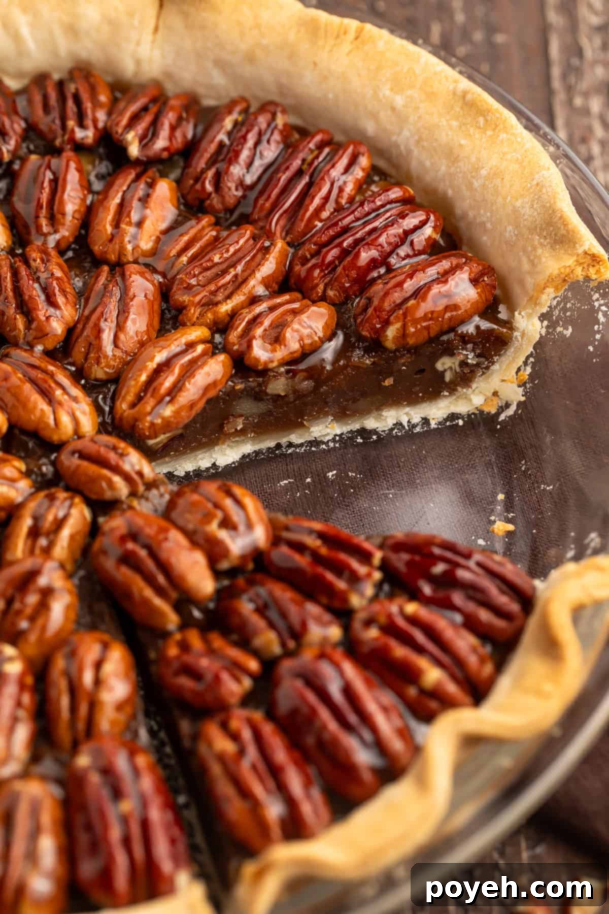 Side-on view of a vegan pecan pie showing the filling with a slice taken out of it.