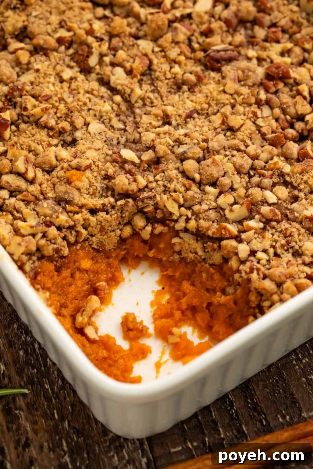 Close up of a sweet potato casserole with a spoonful taken out the corner to show the filling.