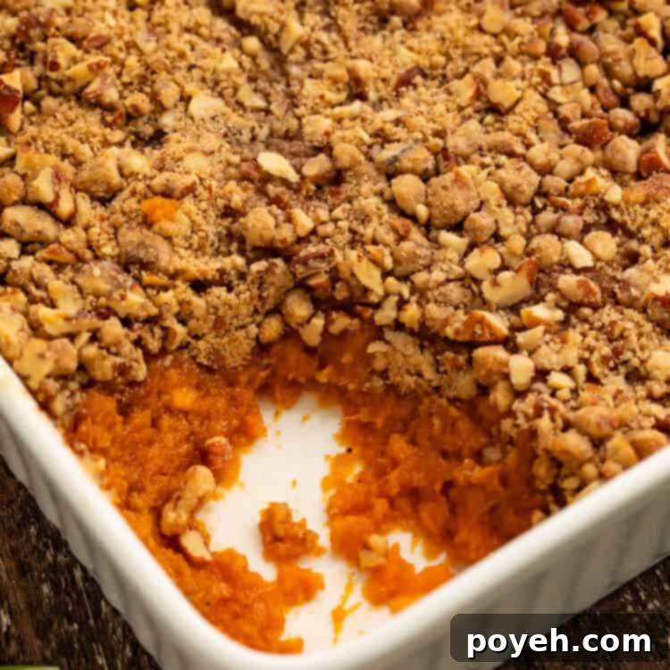 Close up of a sweet potato casserole with a spoonful taken out the corner to show the filling.