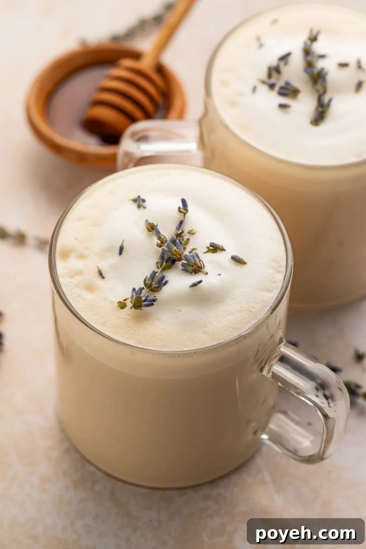 A London fog latte in a clear glass mug sitting on a table, emitting steam.