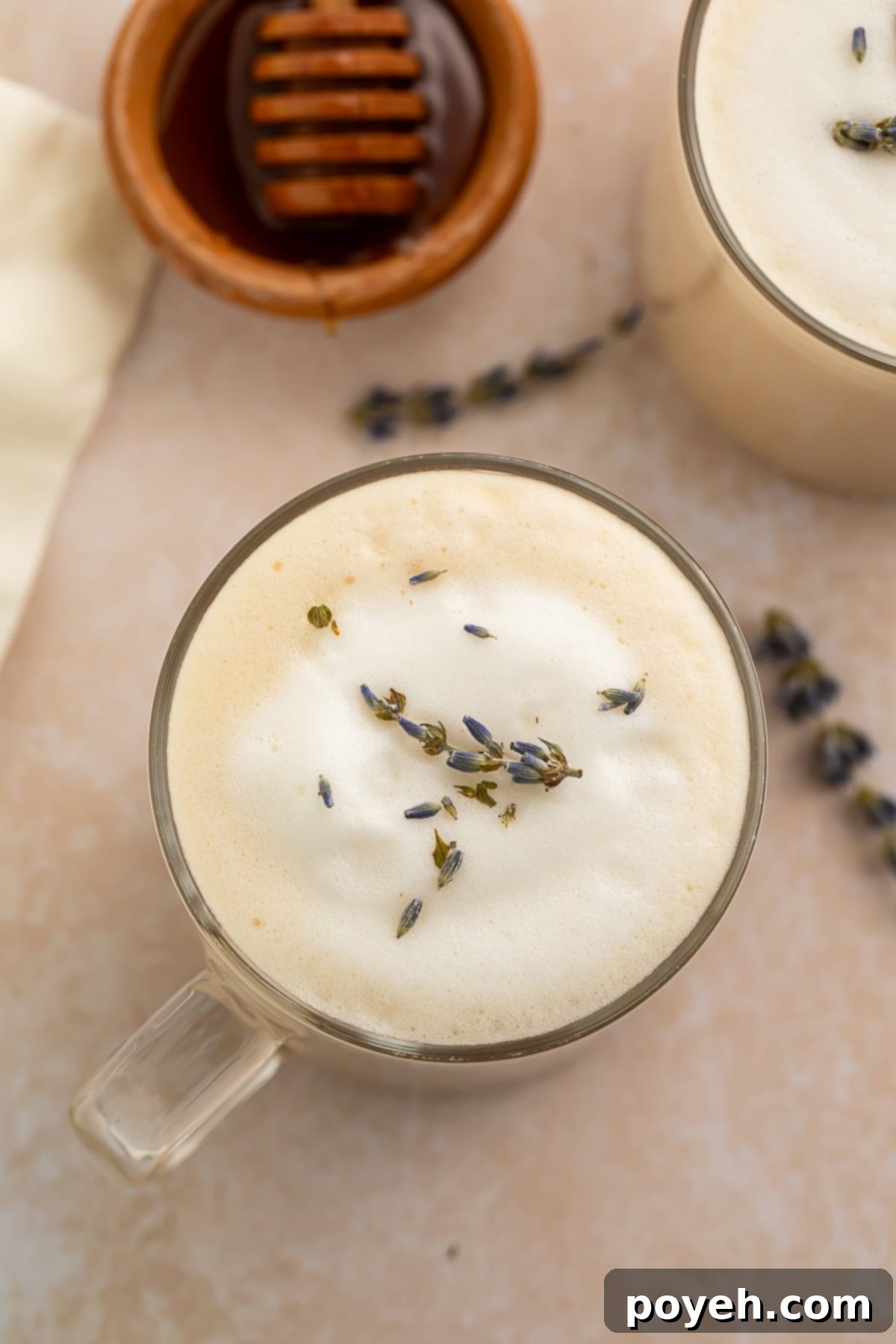 A London fog latte in a clear glass mug on a wooden table, steam rising.