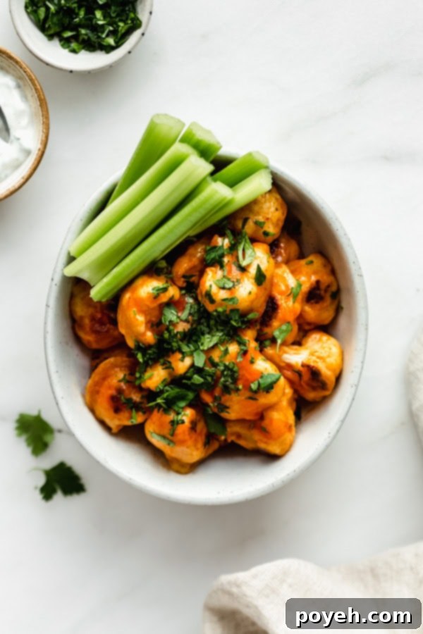 An overhead image of crispy buffalo cauliflower bites served with celery sticks and a cooling dip, perfectly mimicking traditional buffalo wings for a vegetarian snack.