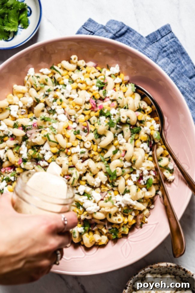 An overhead shot of vibrant Mexican street corn pasta salad, combining pasta with roasted corn, cojita cheese, and a creamy, zesty dressing.