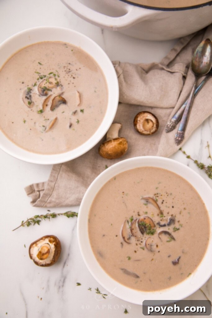 An inviting overhead shot of rich and creamy homemade cream of mushroom soup, garnished with fresh herbs, perfect for a comforting meal.
