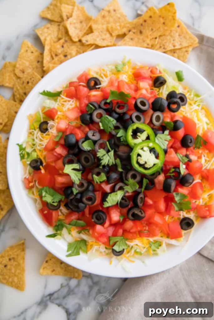 A vibrant image of a layered taco dip, showcasing creamy cheese, fresh salsa, avocado, and other colorful toppings, ready for dipping tortilla chips.