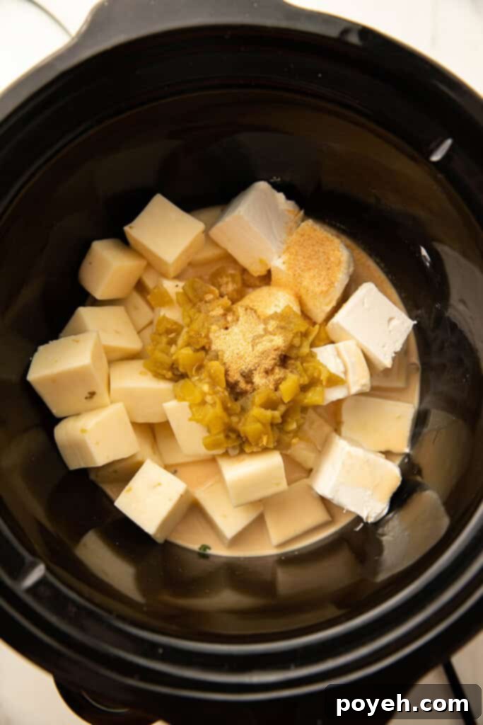 Jalapenos and cubes of cheese being added into a Crockpot