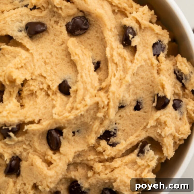 A close-up shot of a generous bowl of edible vegan cookie dough, highlighting its rich, creamy texture and abundant chocolate chips.