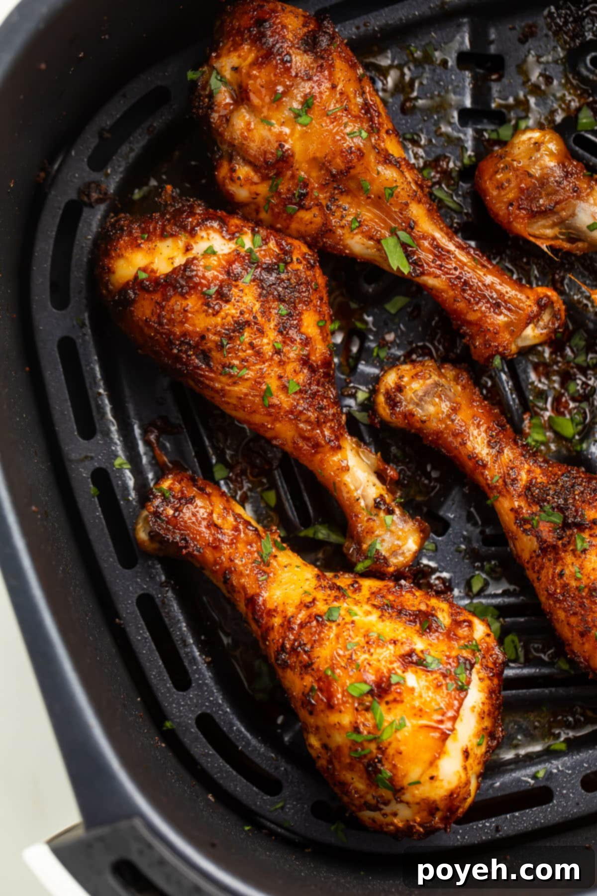 Golden, crispy air fryer chicken legs arranged neatly in a black air fryer basket, ready to be served.
