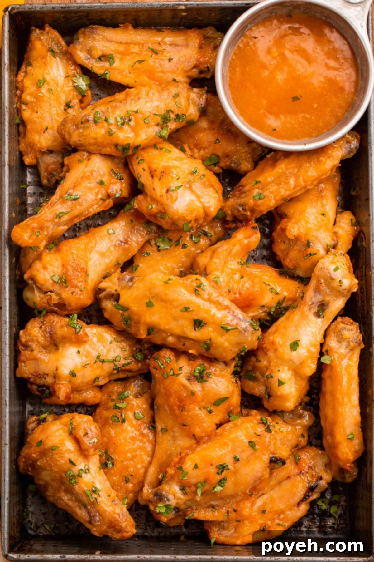 Overhead view of a pan of juicy chicken wings glistening in an orange mango habanero sauce.