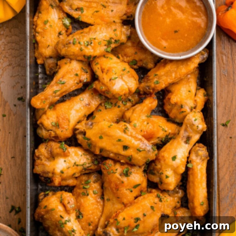 A pan of juicy chicken wings in an orange mango habanero sauce.