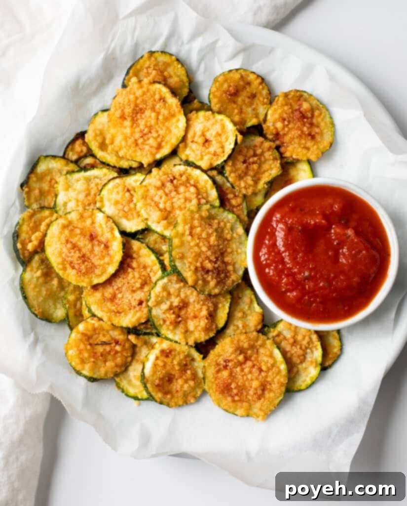 A serving of freshly made, golden brown air fryer zucchini chips arranged neatly on a white plate, ready to be enjoyed as a healthy snack.