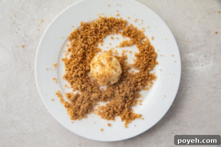 Cream cheese fat bomb rolled in a snickerdoodle crumble on a white plate