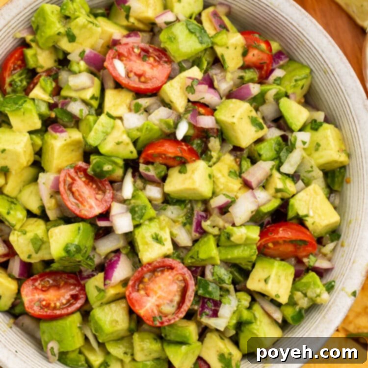 Zesty Chunky Avocado Tomato Salad 4 Close-up view of chunky guacamole salad with avocado and cherry tomatoes in a large white bowl.
