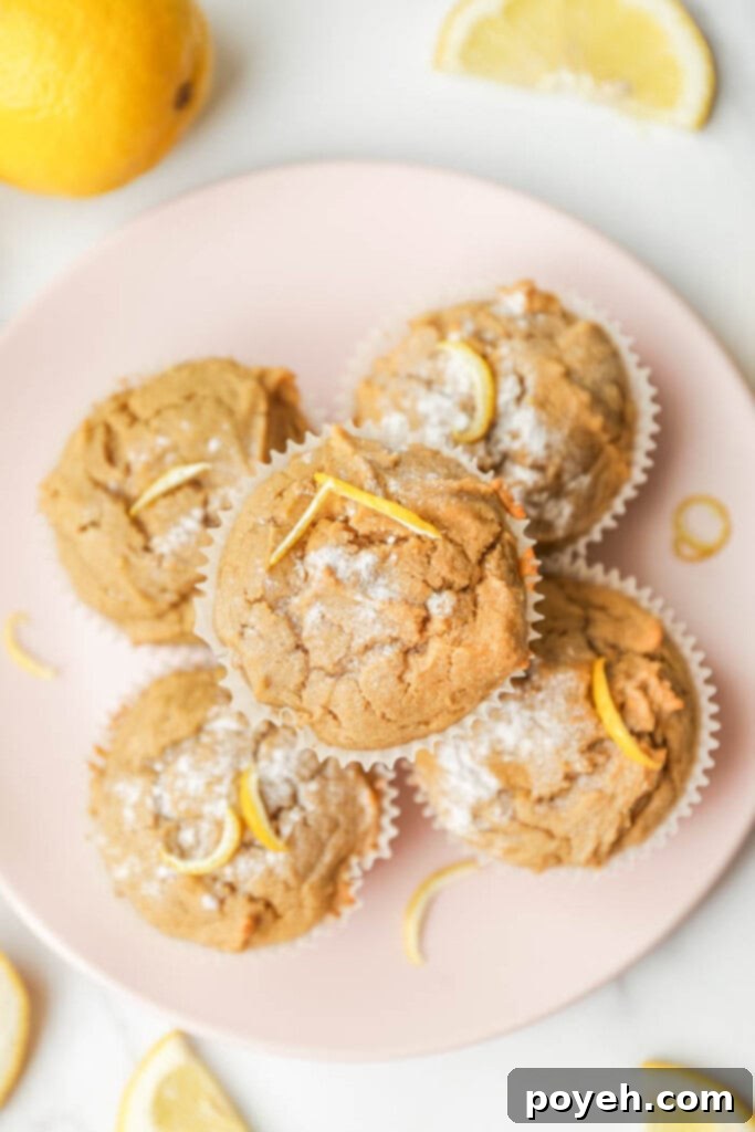 Plate of golden-brown lemon ricotta muffins, garnished with fresh lemon zest and a light dusting of powdered sugar, showcasing their moist texture.