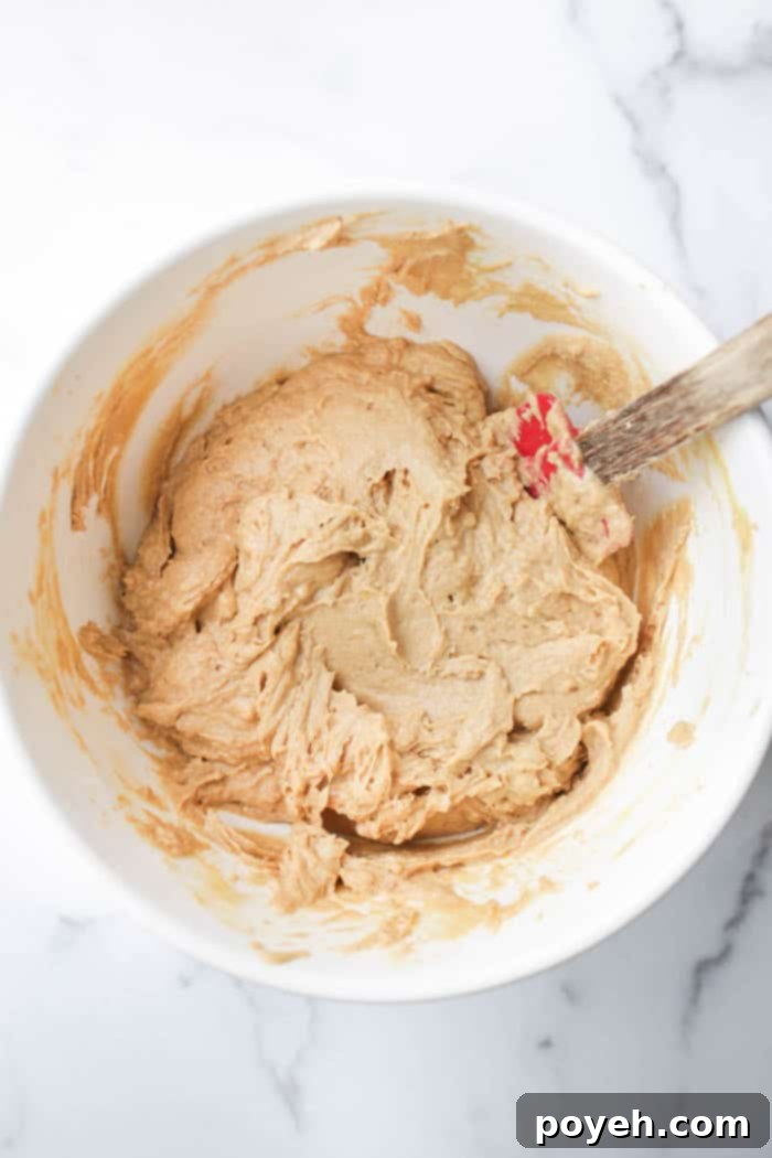 The process of gently folding dry ingredients into the wet batter for lemon muffins.