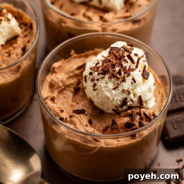 Three glass cups of keto chocolate mousse topped with keto whipped cream and chocolate shavings.