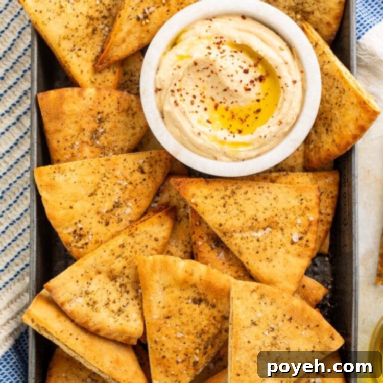 Homemade pita chips in a pan with a small dipping bowl of hummus.