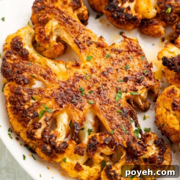 A roasted cauliflower steak on a white plate, seasoned to perfection.