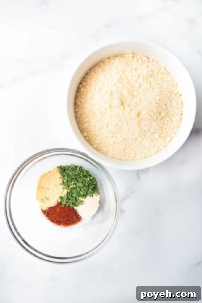 A glass bowl filled with a blend of colorful spices sits beside a white bowl overflowing with grated parmesan cheese, ready for mixing into the cauliflower chips.