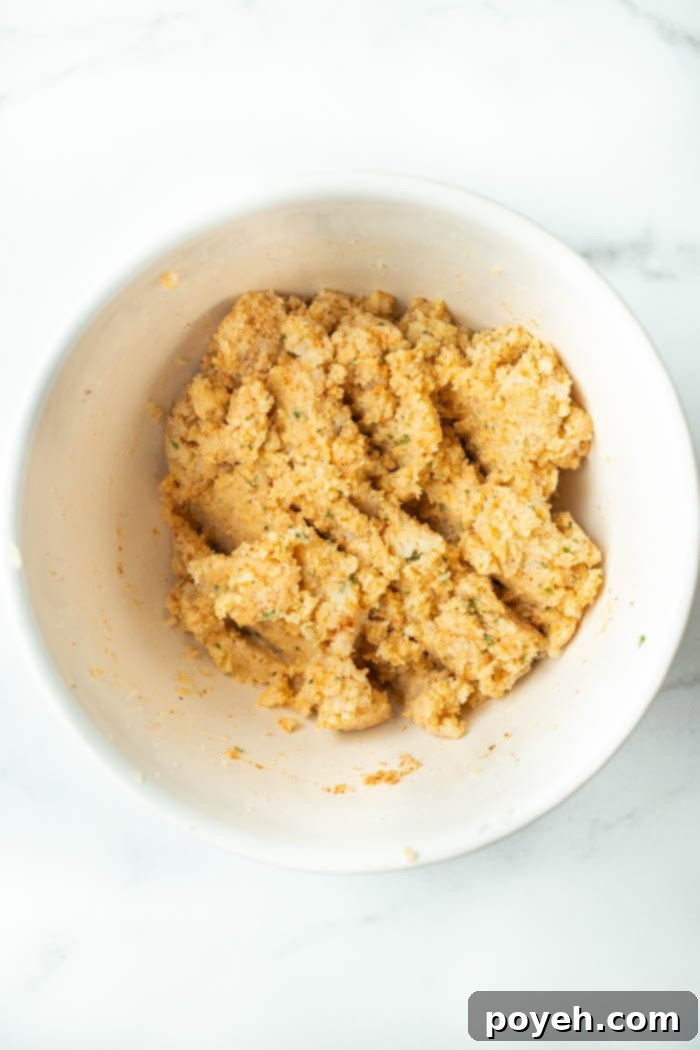 All ingredients for cauliflower chips mixed together in a large bowl, forming a dough-like consistency.
