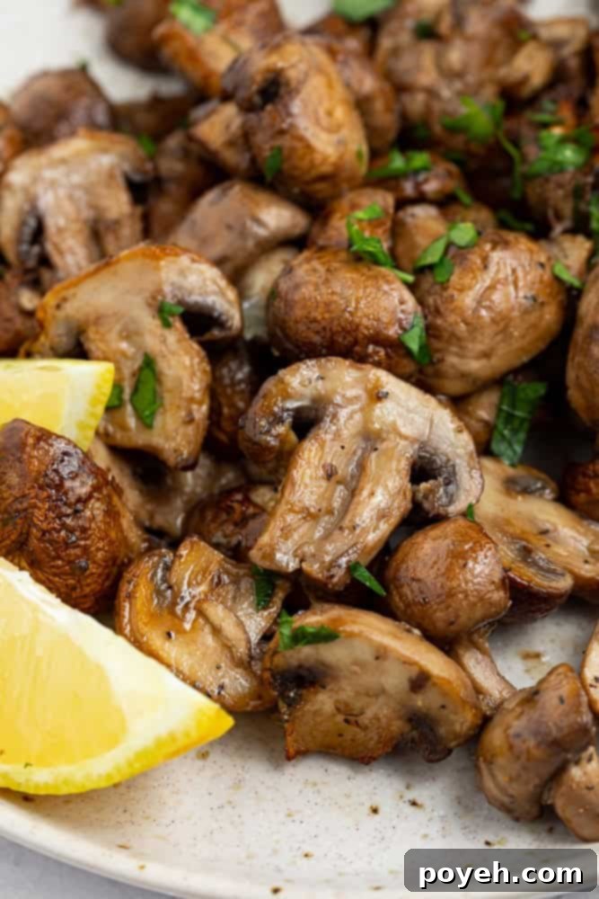 air fryer mushrooms on a plate with fresh parsley and lemon wedges