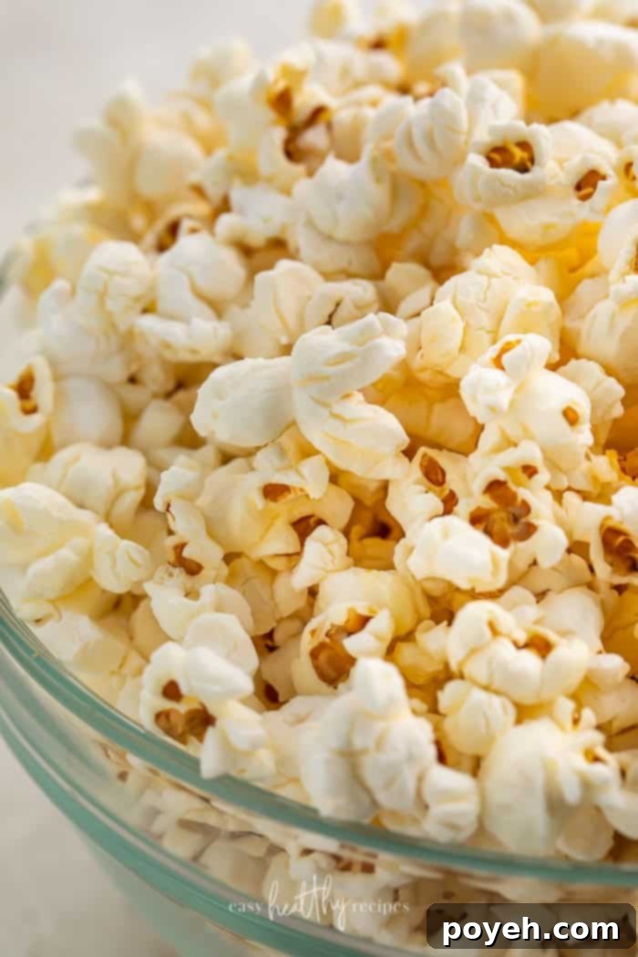 Close-up of air fryer popcorn in a glass bowl, showcasing its fluffy texture and golden hue.