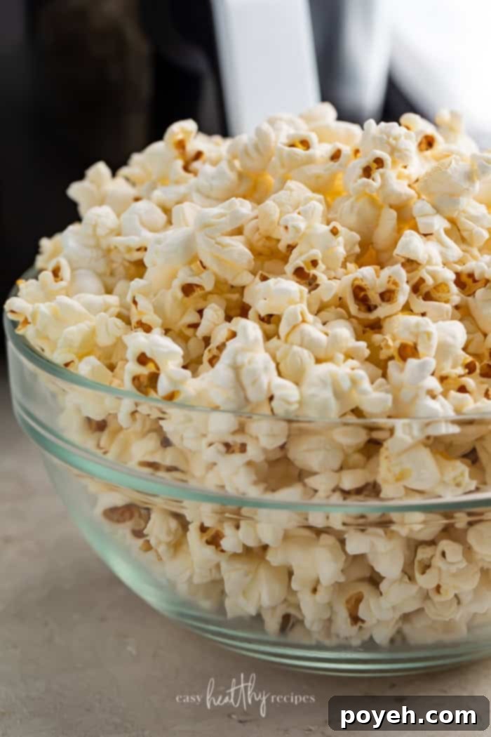 Air fryer popcorn in a glass bowl, ready to be seasoned and enjoyed.