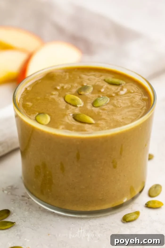 Side shot of a clear glass filled with pumpkin butter garnished with seeds