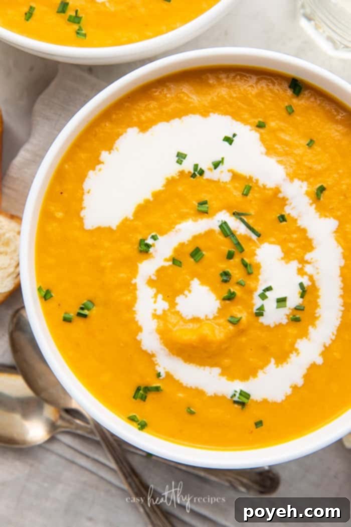 Close-up shot of pumpkin bisque in white bowls garnished with chives and cream