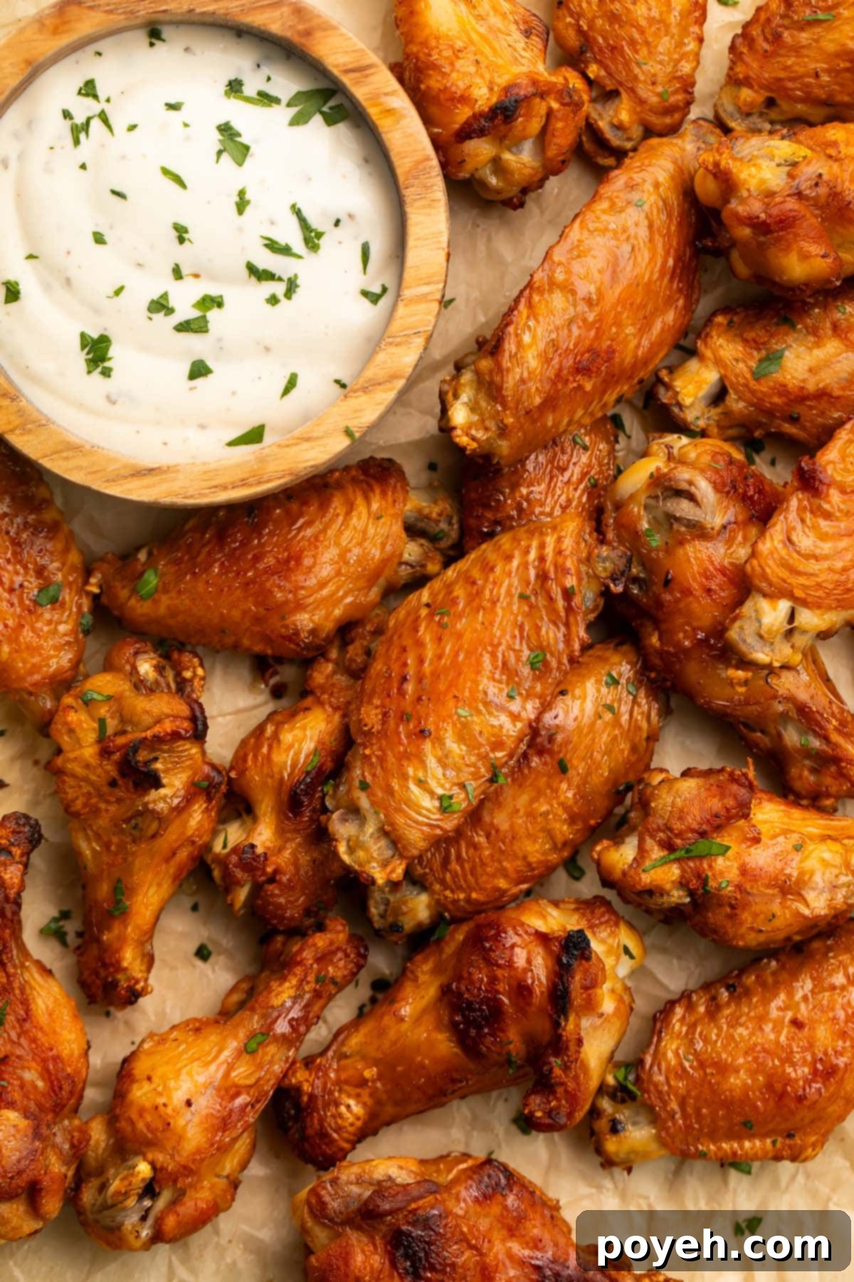 A close-up shot of a hand holding a single perfectly cooked, golden-brown brined chicken wing, showcasing its crispy skin and succulent texture, ready to be enjoyed.