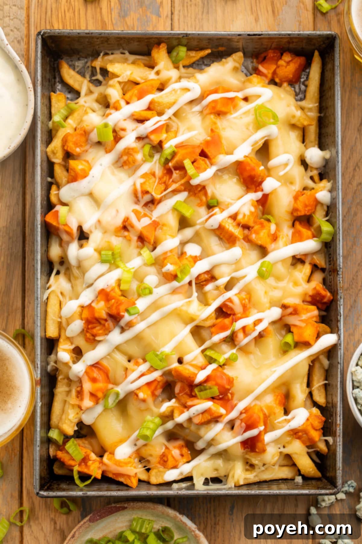 Buffalo Blaze Fries 2 Overhead view of a rectangular baking pan holding french fries topped with buffalo chicken, green onions, and a ranch dressing drizzle.