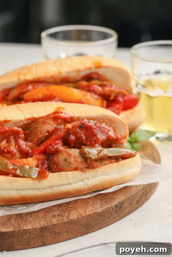 A close-up of a rustic wooden board featuring two Instant Pot sausage and peppers sandwiches, with ingredients scattered around.