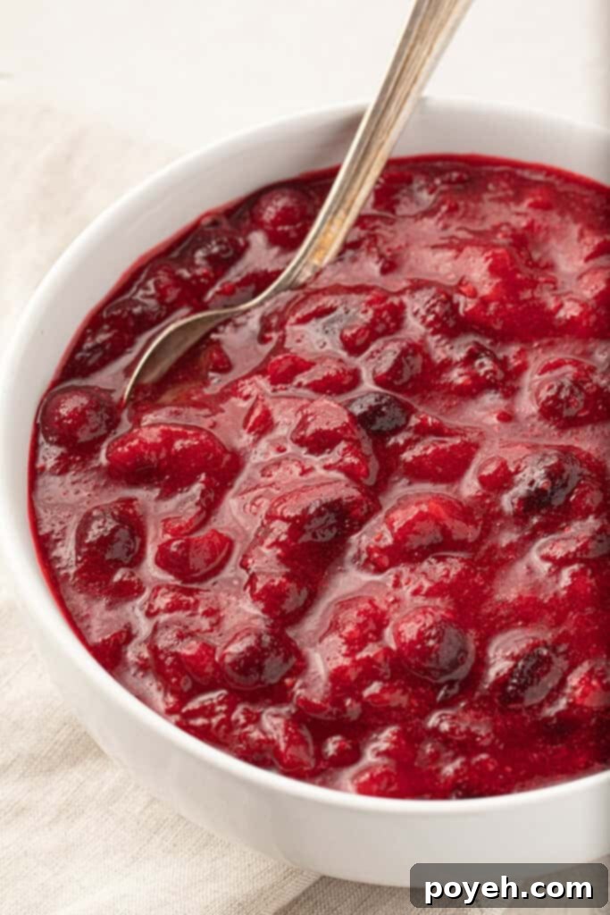 A white bowl of keto cranberry sauce with a spoon in it