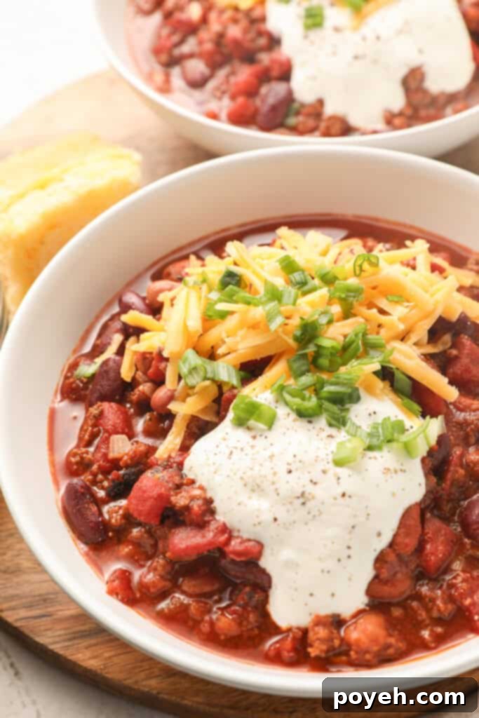 A bowl of bison chili topped with sour cream, cheese, and scallions
