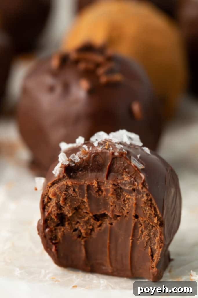 Half eaten truffle topped with sea salt, showcasing the creamy interior.