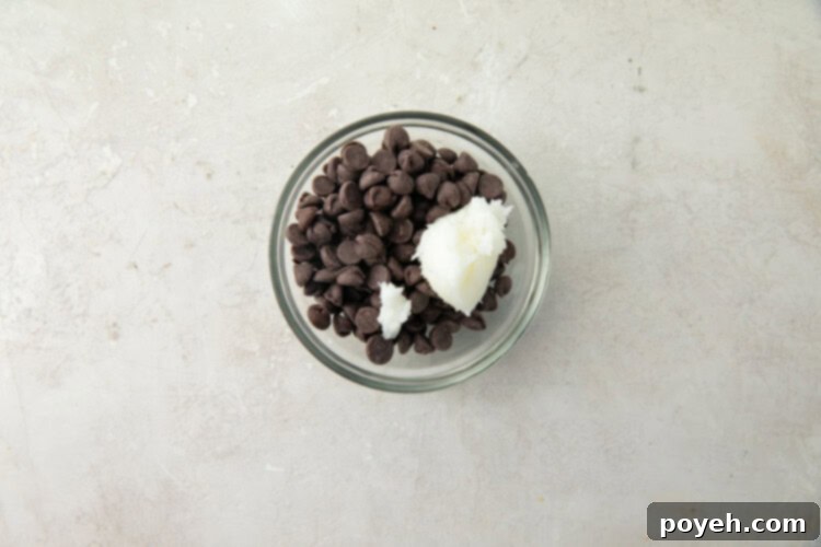 Small glass bowl containing chocolate chips and coconut oil, ready for melting.