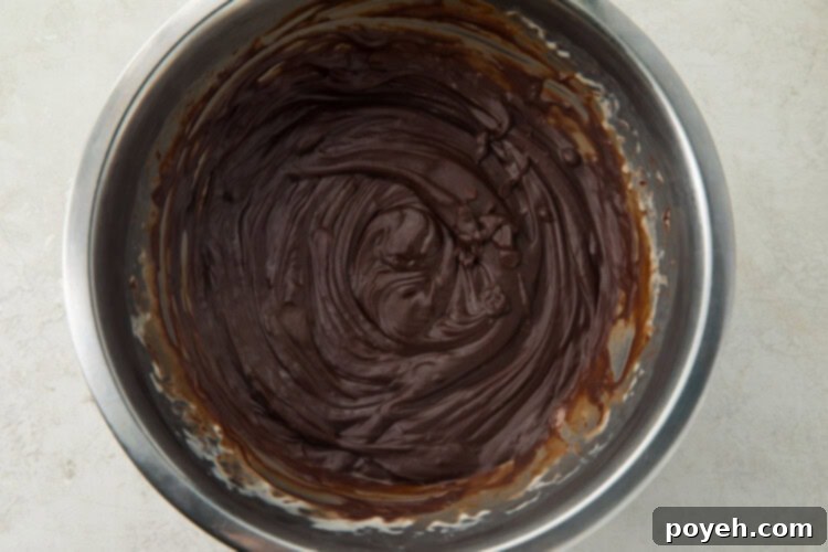 Melted chocolate in a large silver saucepan, demonstrating the smooth ganache texture.