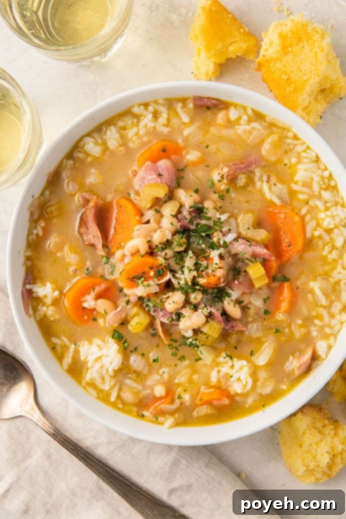 A beautifully presented bowl of smoked turkey soup, showcasing carrots, celery, and white beans, set against a pristine white table.