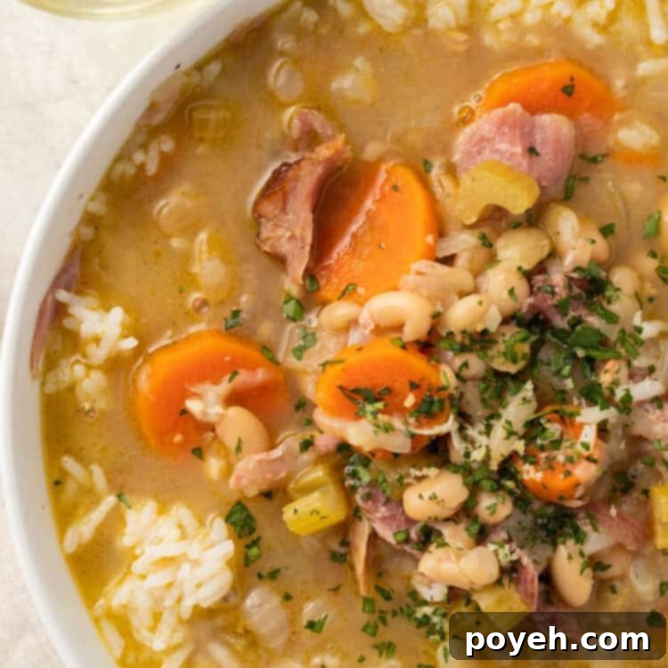 White soup bowl with smoked turkey soup, carrots, celery, and Great Northern beans