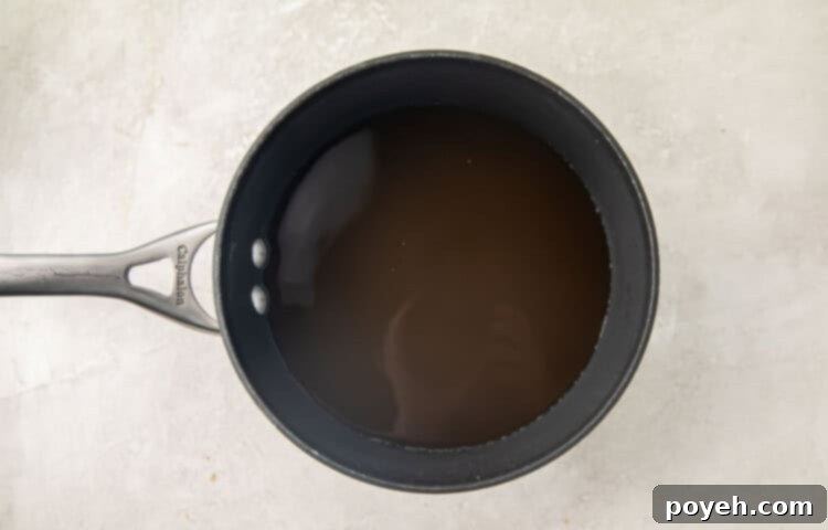 Broth and water simmering in a silver pot, beginning to boil.