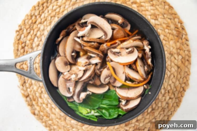 Chinese vegetable soup simmering in a silver pot, with bok choy, carrots, and mushrooms added.