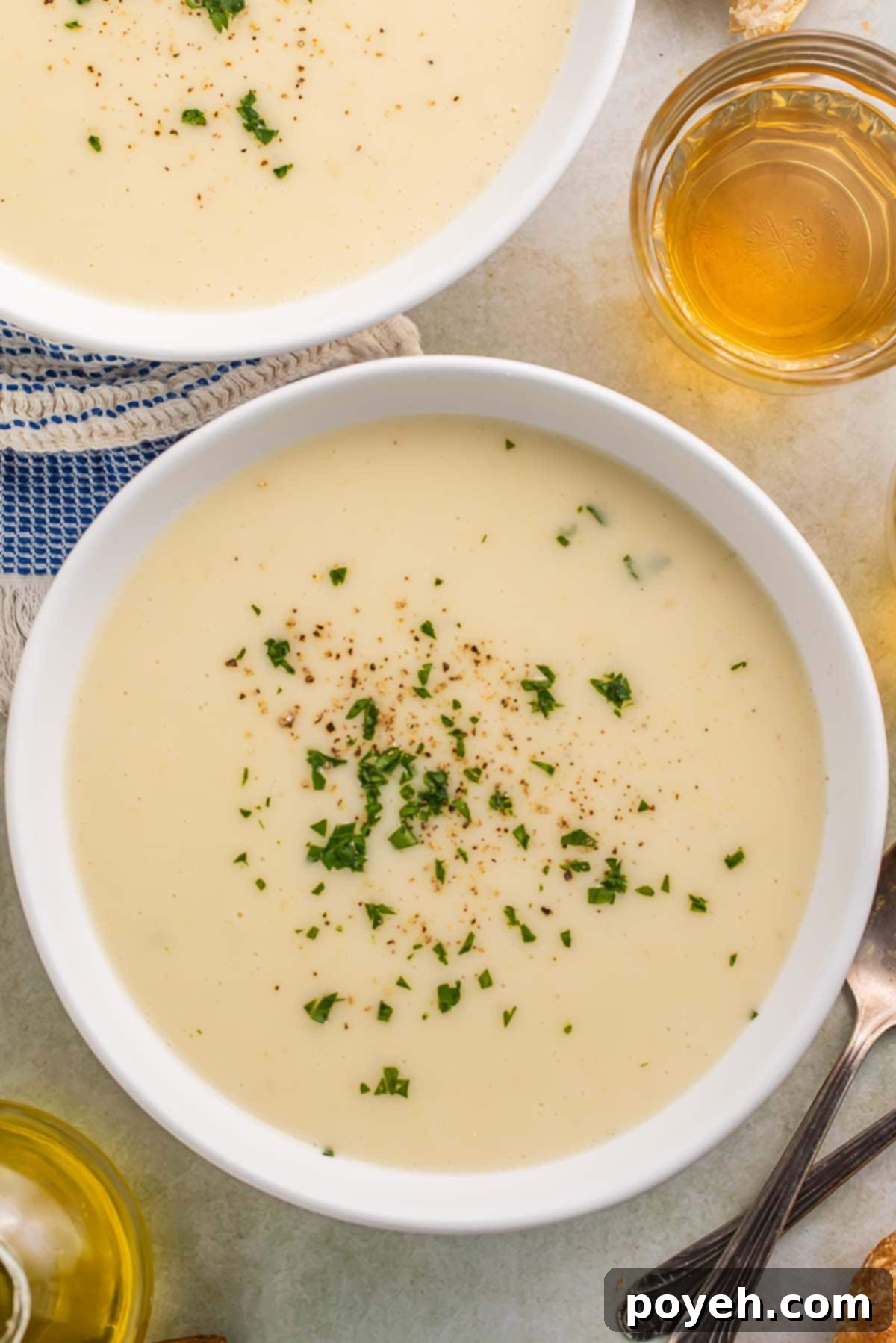 Close-up of a bowl of Irish potato soup on a rustic wooden table, garnished with fresh herbs.