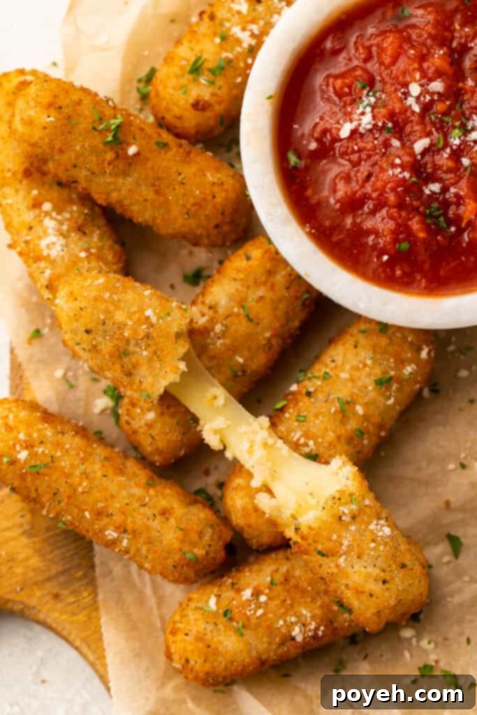 Frozen mozzarella sticks cooked in the air fryer then placed a on a white plate with a small bowl of marinara