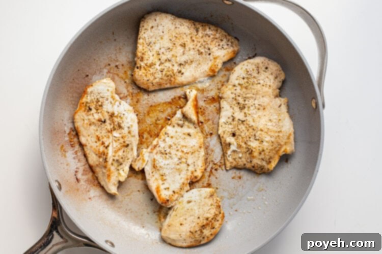 Chicken cutlets in a large grey skillet.