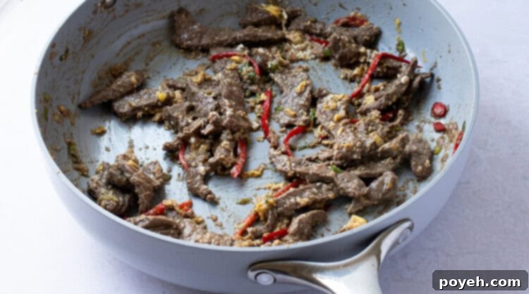 Beef and scrambled egg mixing in a large skillet.