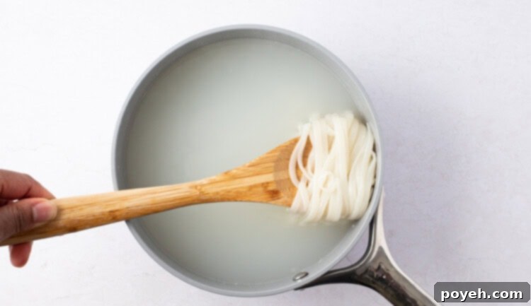 Pad Thai noodles soaking in hot water in a saucepan.