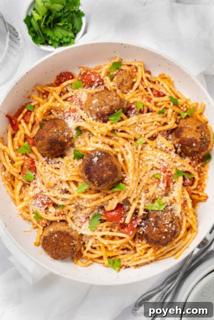 Keto spaghetti and meatballs on a plate with parmesan cheese and chopped parsley.